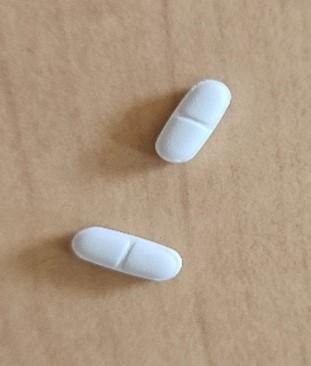 2 comprimés (médicaments) posés sur une table en bois
