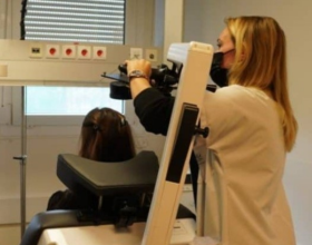 Une personne manipule le bras d'une machine de stimulation magnétique transcranienne pour délivrer le traitement à une personne allongée de dos dans un fauteuil