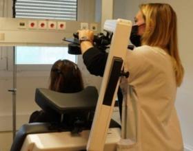 Une personne manipule le bras d'une machine de stimulation magnétique transcranienne pour délivrer le traitement à une personne allongée de dos dans un fauteuil